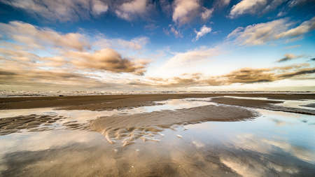 A beautiful shot of the seashore with water ponds under a blue sky