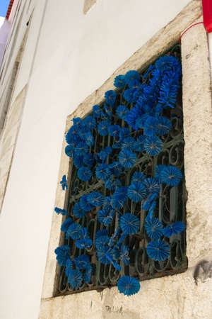 A vertical low angle shot of a blue paper flowers decorating a windowの写真素材