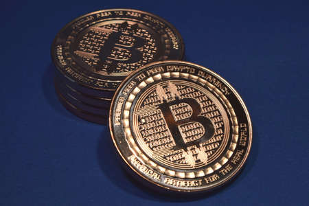 A closeup of bitcoins under the lights against a blue background