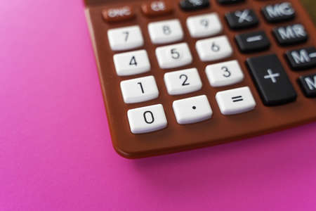 A closeup shot of a red calculator on a pink surfaceの写真素材