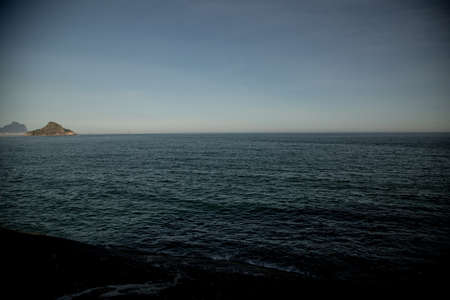 A blue sea with a small island on the left in  Rio Brazil