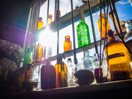 A lot of jars and bottles of old pharmacy on the shelf with the bright sun in the backgroundの写真素材