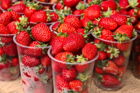 A high angle closeup shot of glasses of strawberries in a fruit marketの写真素材