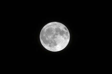 A landscape shot of a white full moon with black color in the backgroundの写真素材