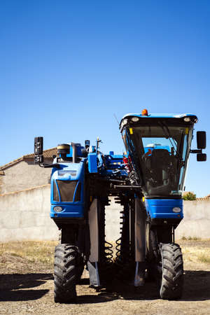 A vertical shot of a grape harvesting machine during daytime
