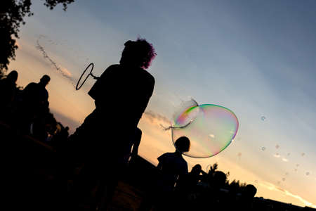A silhouette shot of a man playing bubble in a party with a  beautiful sunset scenery