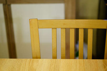 A closeup shot of the upper part of a wooden chair with a blurry background