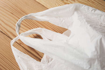 A high angle shot of a white plastic bag on wooden surface