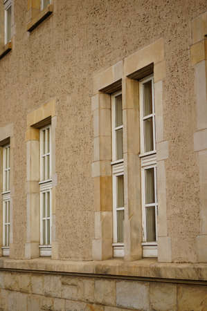 A vertical low angle shot of the windows of a stone building with a beige facade