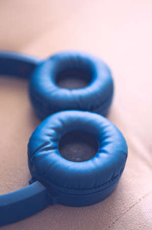 A vertical closeup shot of blue headphones with a blurred backgroundの写真素材