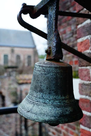 A vertical closeup shot of a stone bell hanged on the wall of a cobblestone buildingの写真素材