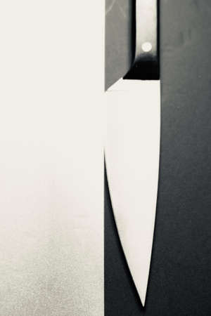 A vertical grey scale shot of a knife on a black and white surface captured from a high angleの写真素材