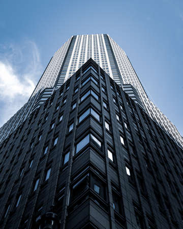 A low angle shot of a tall city building with a blue sky in the background  in New York