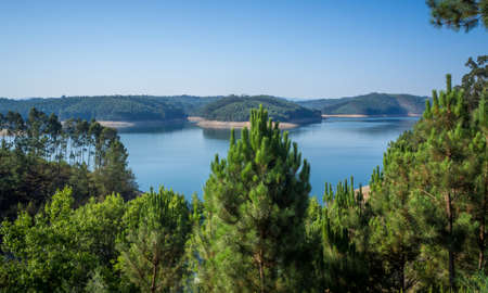 A high angle shot of a beautiful lake below the green spruce trees
