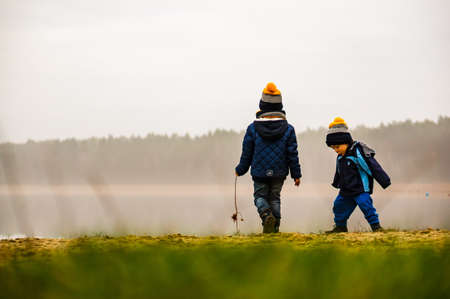 DECZNO, POLAND - Dec 25, 2019: Two kids standing close by a lake on a cold and misty day.
