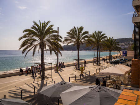 SESIMBRA, PORTUGAL - Mar 30, 2019: View of the coastal town of Sesimbra with palms on the street and beach in Portugalのeditorial素材