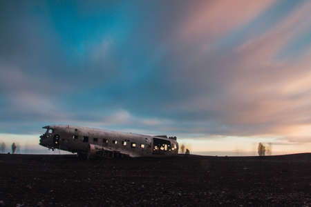 The Abandoned DC plane on Solheimasandur surrounded by people under a cloudy sky during the sunset