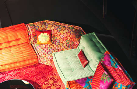 A high angle shot of a sofa with colorful textiles with a black background