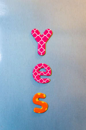 A vertical shot of colorful words spelling out yes in a line