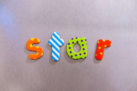 The word star made of colorful magnetic letters on a brown backgroundの写真素材