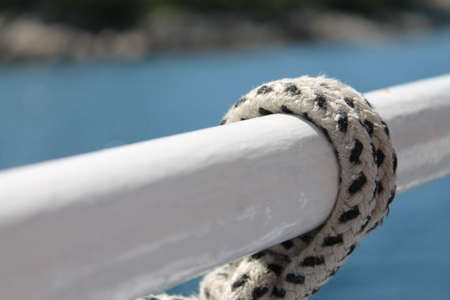 A closeup shot of a black and white rope tied in a metal handle with a blurred background
