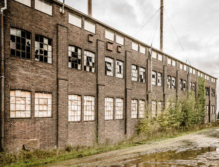 An old abandoned stone building with broken windows and a puddle outsideの写真素材