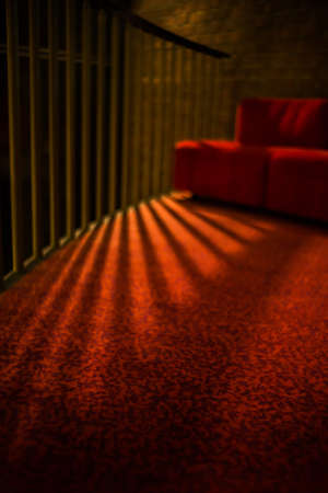 A vertical shot of a balcony with metal bars and a red couchの写真素材