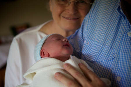 A grandmother looking at a newborn child under the lights with a blurry backgroundの写真素材