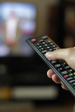 A vertical shot of a person using a television remote