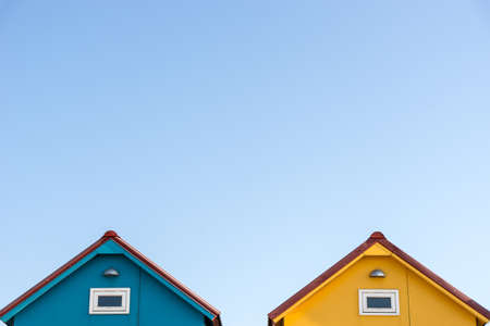 The roofs of small blue and yellow houses with a light-colored backgroundの写真素材