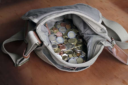 A bag filled with coins on a wooden surfaceの写真素材