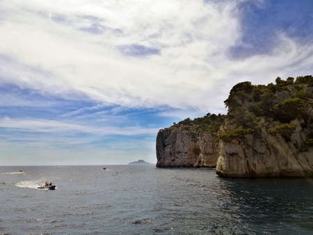 The Massif des Calanques surrounded by the sea under a cloudy sky and sunlight in France