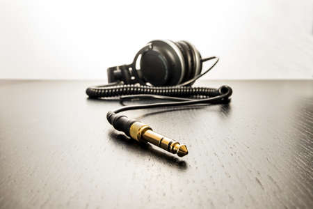 A closeup of the cable of black headphones on the table under the lights against a white background