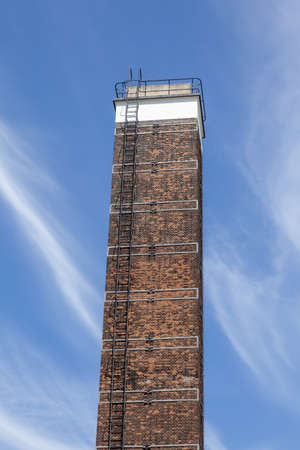 A low angle view of an old chimney under a blue sky and sunlightの写真素材
