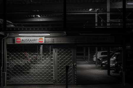 A grey-scale view of different cars in an indoor parking lot