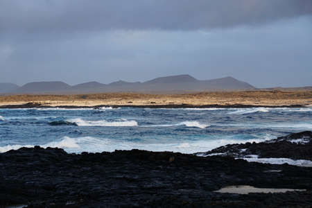 A beautiful shot of the rocky beach and mountains in the background in Fuerteventura, Spain