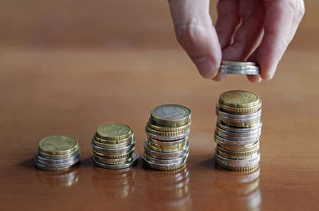 A closeup shot of a person putting a coin on the coin stack