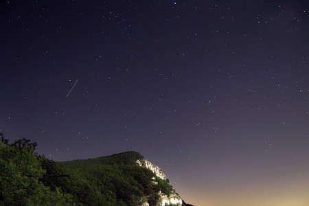 A beautiful shot of a mountain cliff with a starry night purple sky in the background