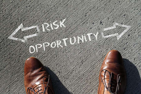 A high angle shot of risk and opportunity marked with opposite directions on the groundの写真素材