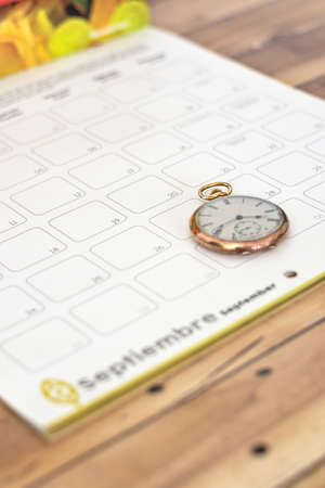 A clock on a planner on a wooden table - time management concept