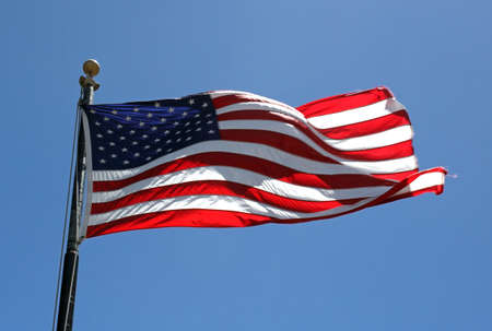A low angle shot of the flag of the United States under a blue sky