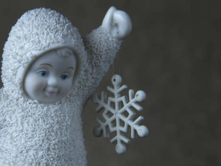 A closeup shot of a cute baby angel statuette holding a snowflakeの写真素材