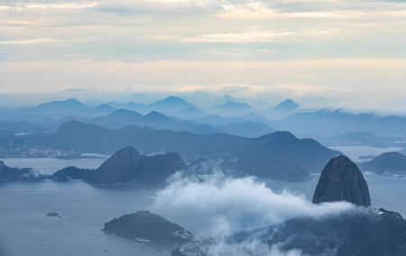 A bird's eye view of an ocean with mountains surrounded by cloudsの写真素材