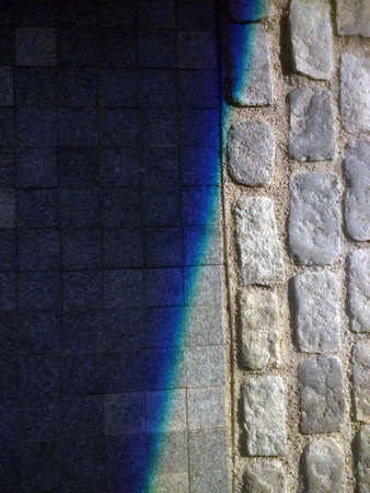 A vertical shot of a shadow covering a surface made of rectangular and square stonesの写真素材