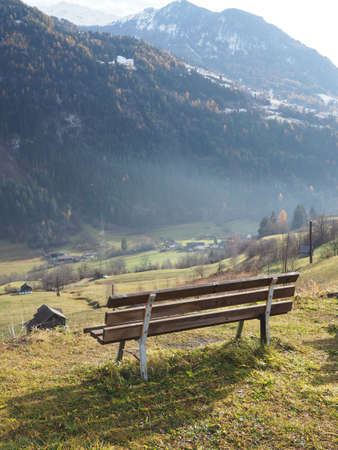 A closeup shot of a wooden bench with a big mountain in the backgroundの写真素材