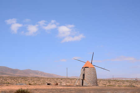 A wide shot of a windmill with a clear blue sky in the background