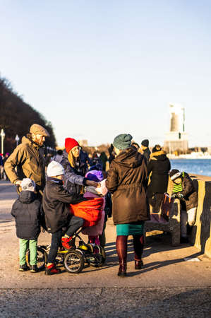 GDYNIA, POLAND - Jan 05, 2020: Parents and kids with buggy on a footpath along the sea on a cold winter day.のeditorial素材