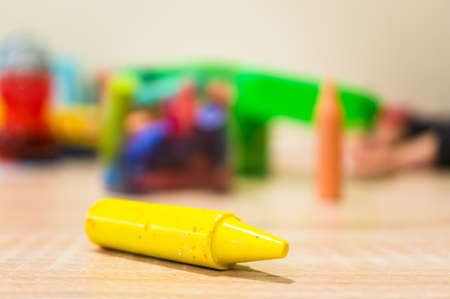 A closeup shot of a yellow crayon on a wooden surface