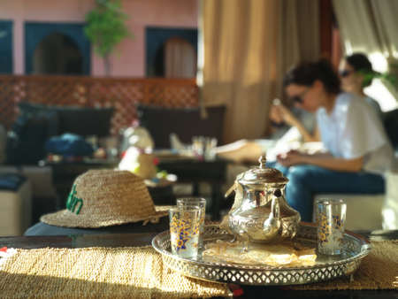 A selective focus shot of a kettle and glasses for traditional Moroccan tea with mint in a cafeの写真素材