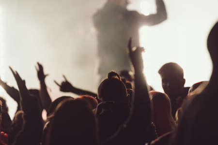 People dancing at a concert while the singer is performing surrounded by lights